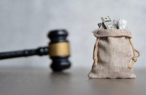 Closeup image bag of money and judge gavel. Lawsuit, auction, bribe and penalty concept.